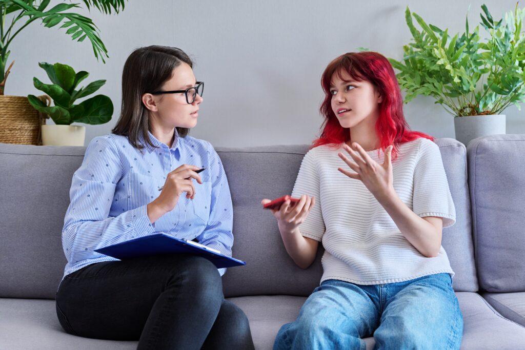 Psychologist for teenagers working with adolescent female in office.